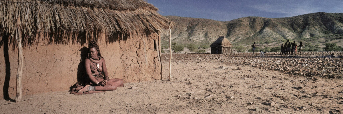 Himba Kraal by Koos van der Lende, a Himba woman outside a kraal