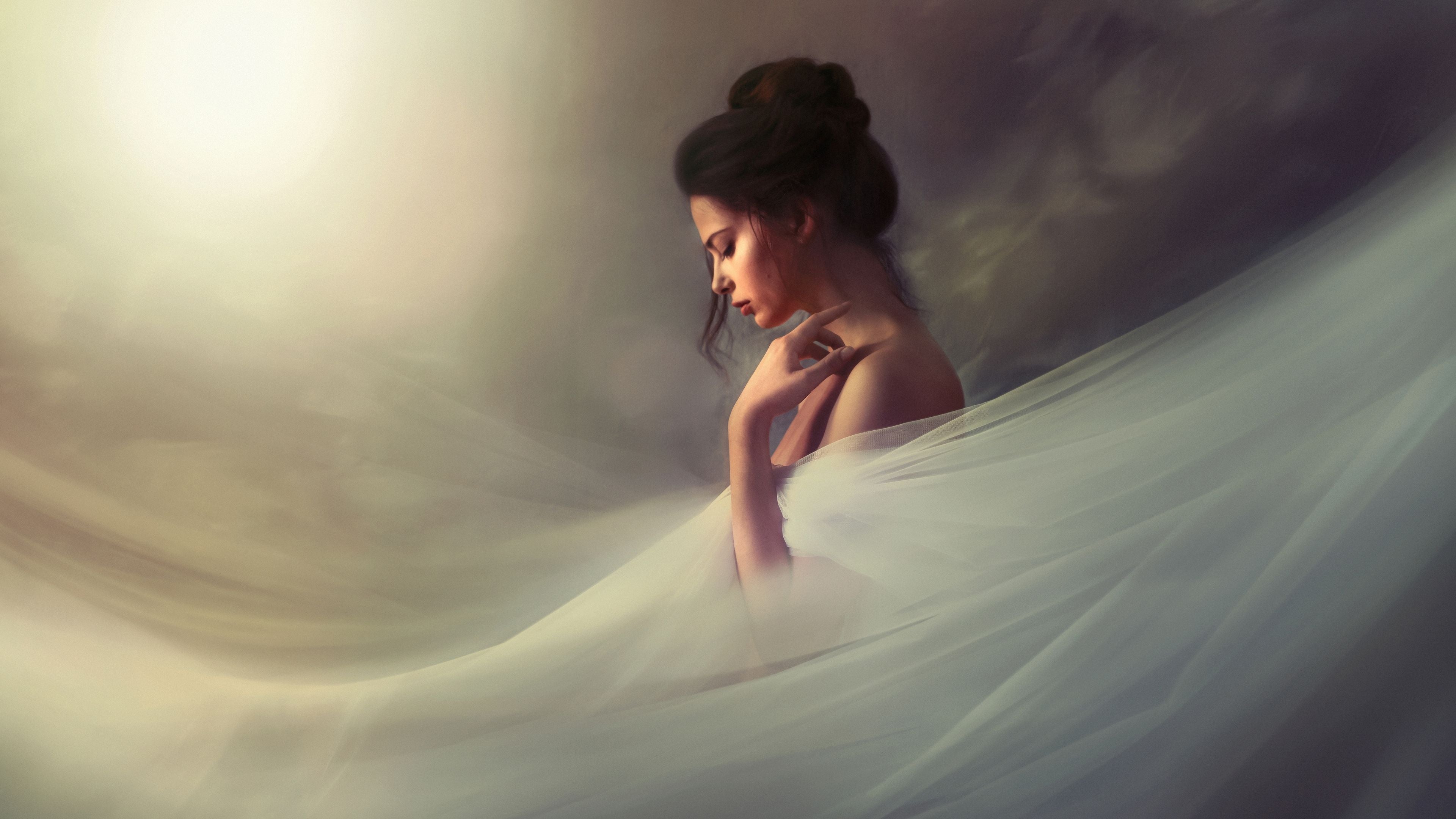 Fine art portrait of a woman in soft flowing fabric, posed in profile with gentle light and a serene, introspective expression
