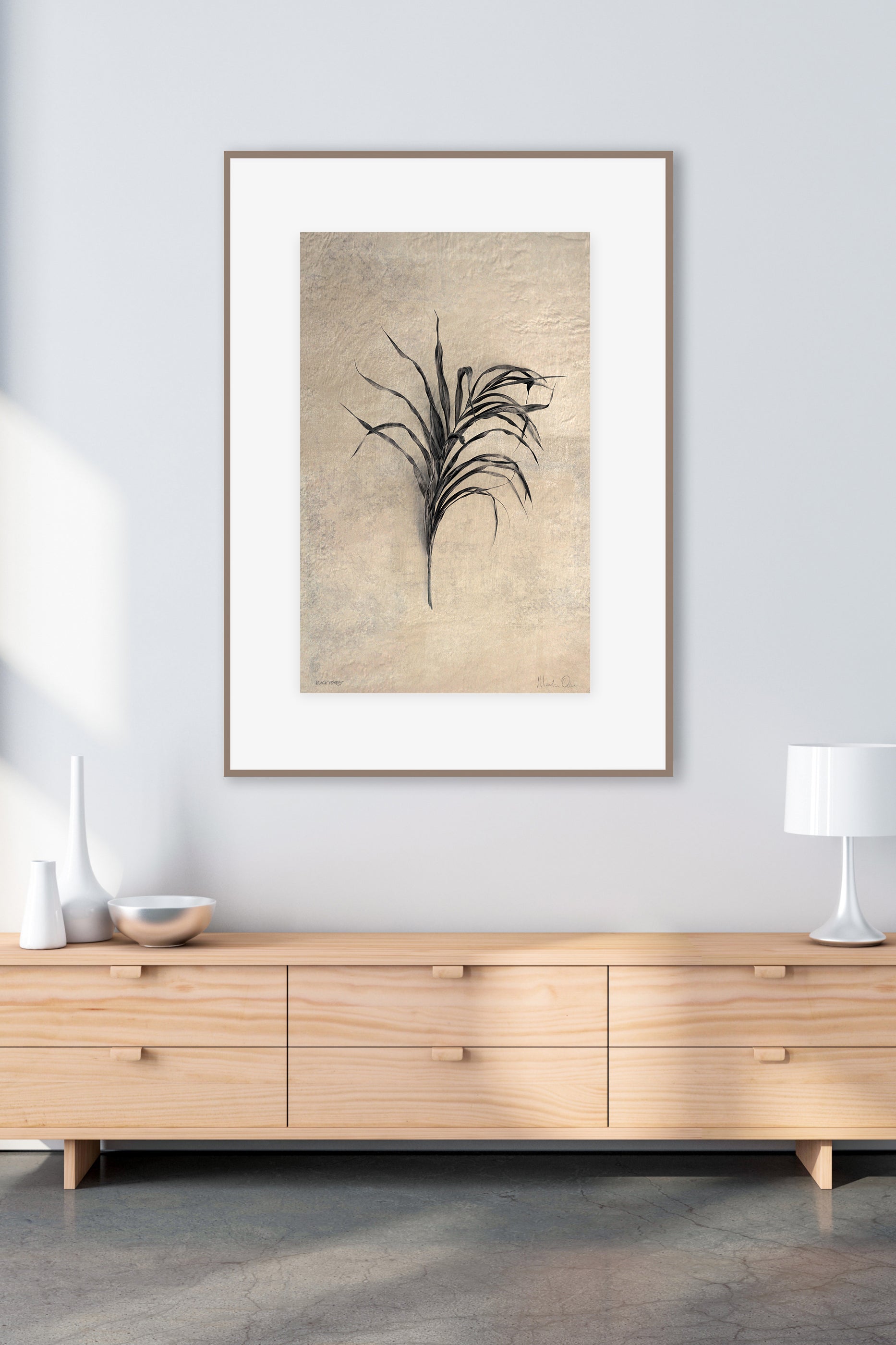 Framed artwork of a plant on a wall above a wooden cabinet.