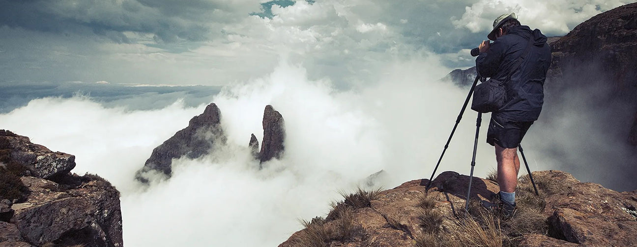 Fine art landscape photographer Hougaard Malan capturing a mountain scene above the clouds with his camera and tripod