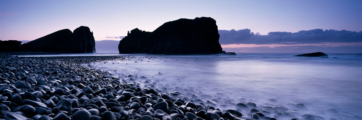 Hole in the Wall, Wild Coast by Koos van der Lende, the arched cliff in silhouette before sunrise above dark rounded rocks