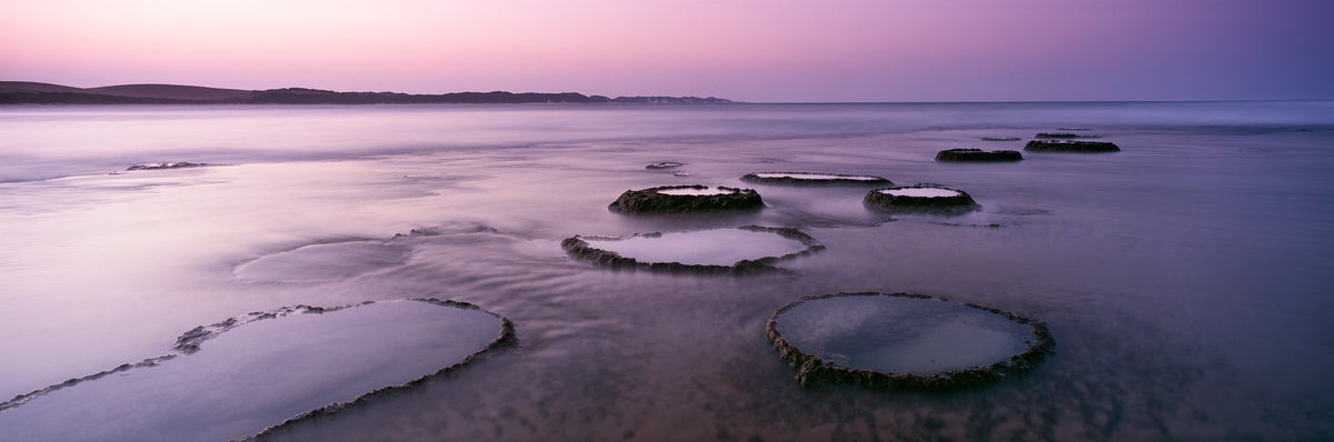 Milibangalala Rocks, Mozambique by Koos van der Lende, rings of rock in a calm pink and lilac sea at twilight