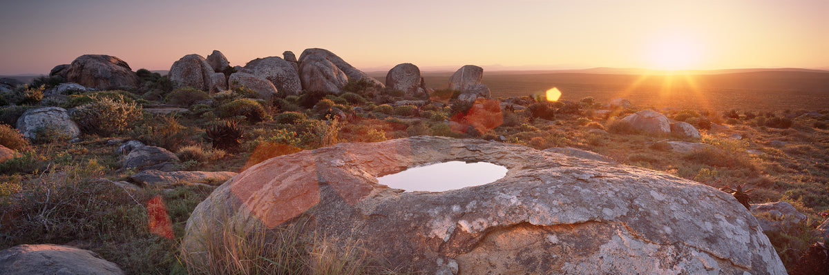 Sunrise, Namaqua by Koos van der Lende, the sun rising over granite boulders